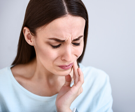 woman holding her jaw in pain
