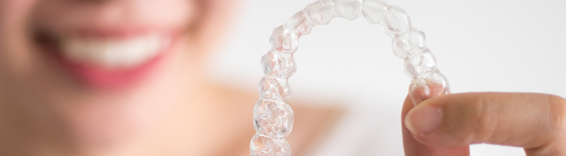 woman holding up a clear aligner